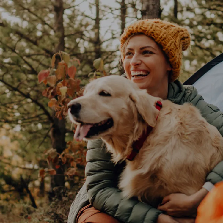A woman holding a dog in a tent