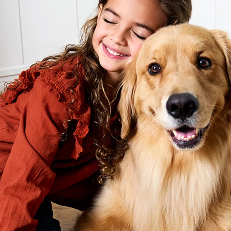A girl hugging a dog while sitting on the floor