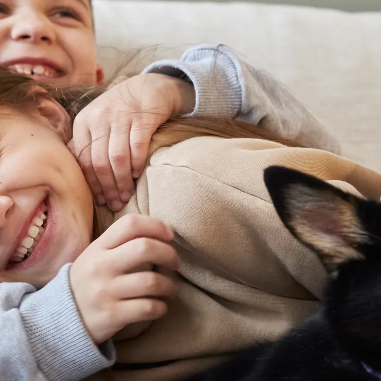 A boy and girl lying on a couch with a dog